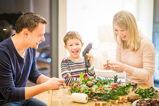 egy nő, egy férfi és egy kisfiú adventi koszorút készít