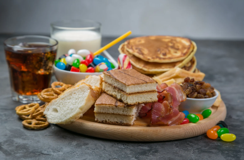 egy tál sütemény kenyér, palacsinta, cukrok, és egy pohár üdítő illetve tej